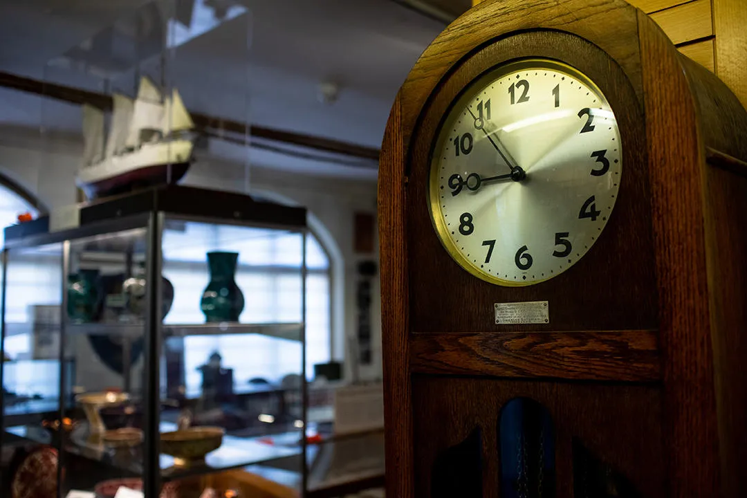 Antique Clock in the foreground, blurry shelves with artefacts in the background